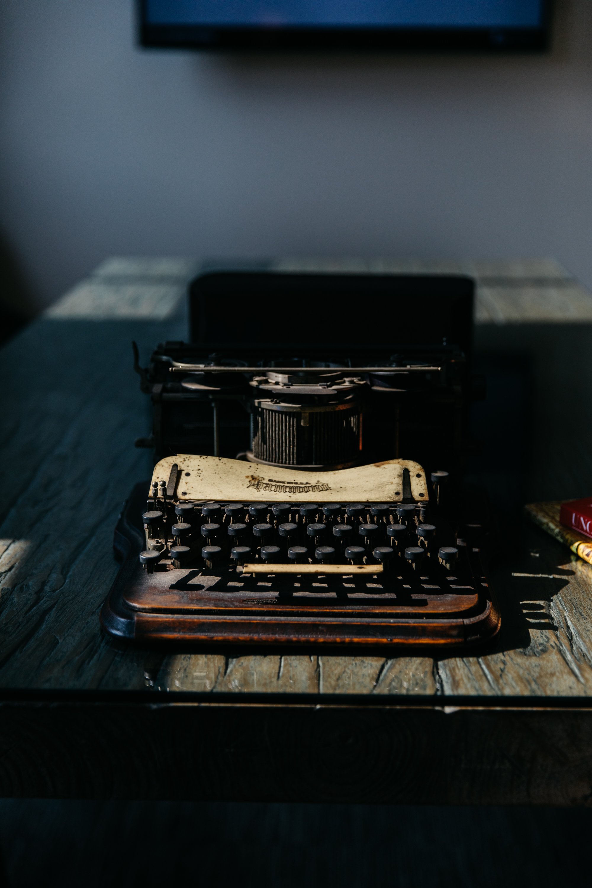 Vintage typewriter on a rustic wooden table with a dark background.
