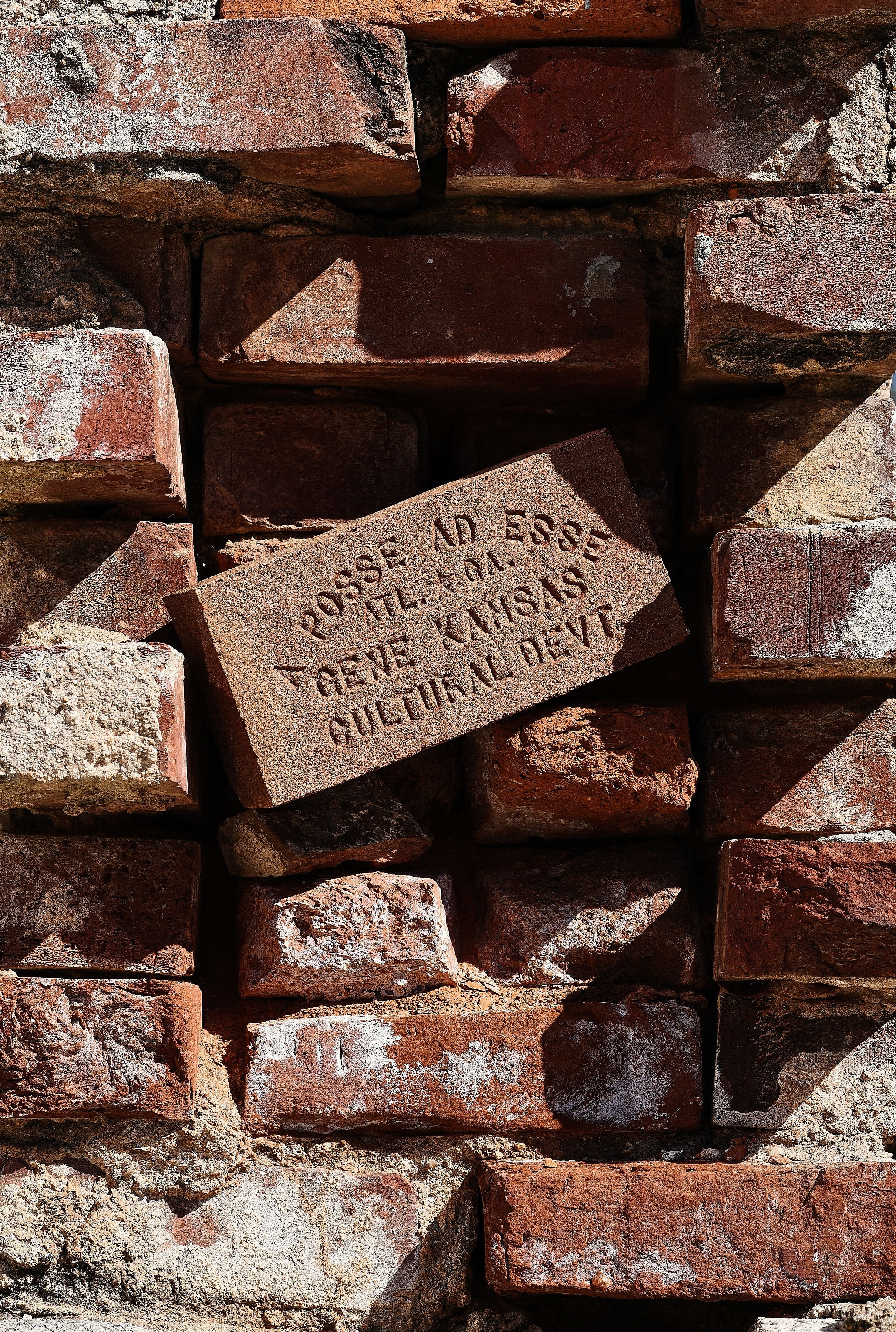Close-up of a brick wall with a carved brick that reads, 'POSSE AD ESSE * THE * KANSAS * CULTURAL * DEV.'