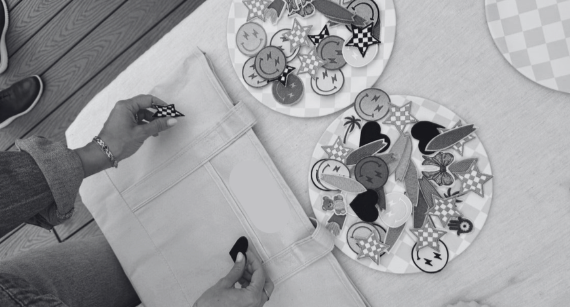 Person adding patches and accessories to tote bag.