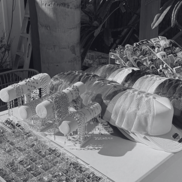 Display of charms, chains, and accessories for hats arranged on a table at an outdoor market.