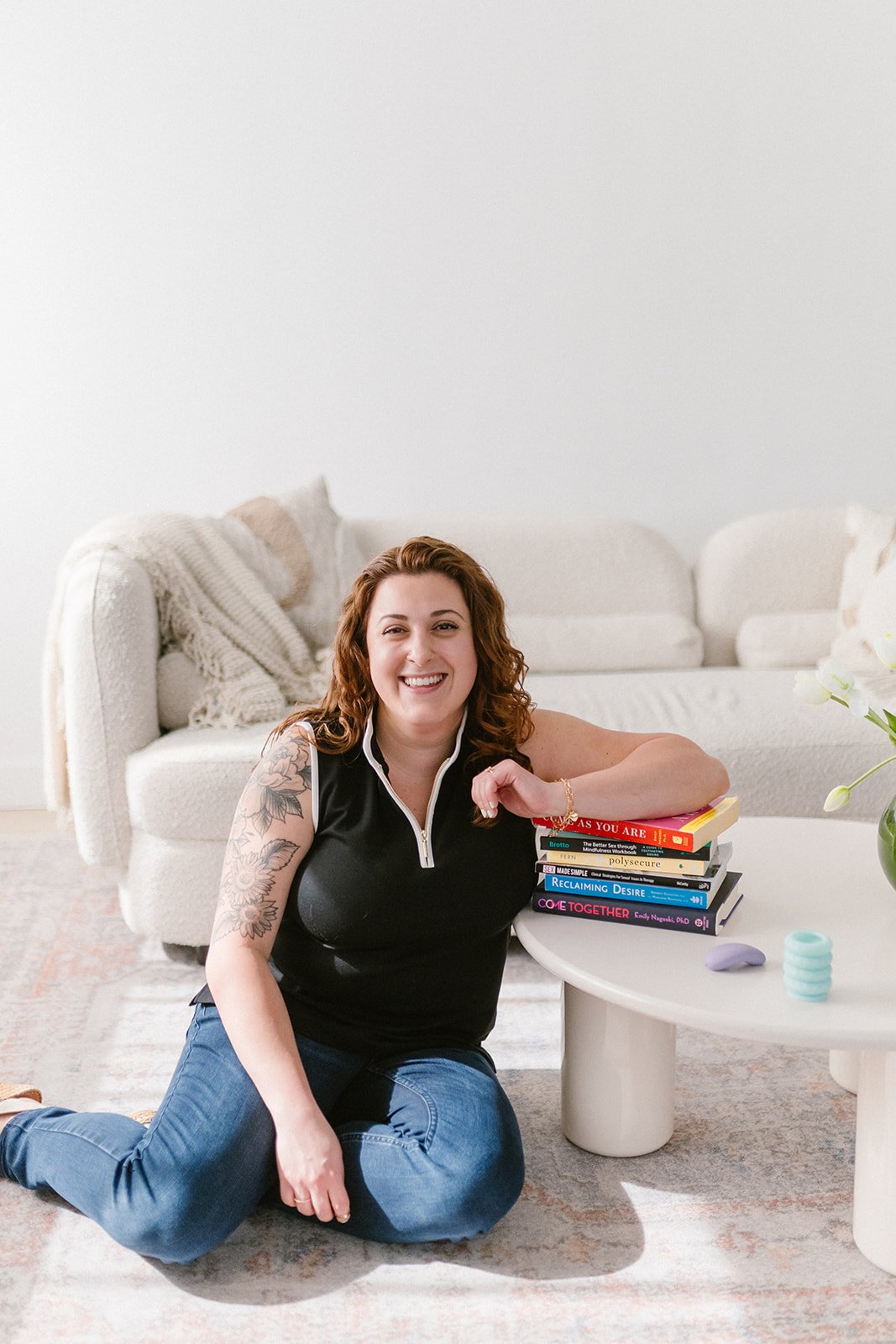 diana sadat sits with a stack of books on the topic of sex and sexuality for therapists