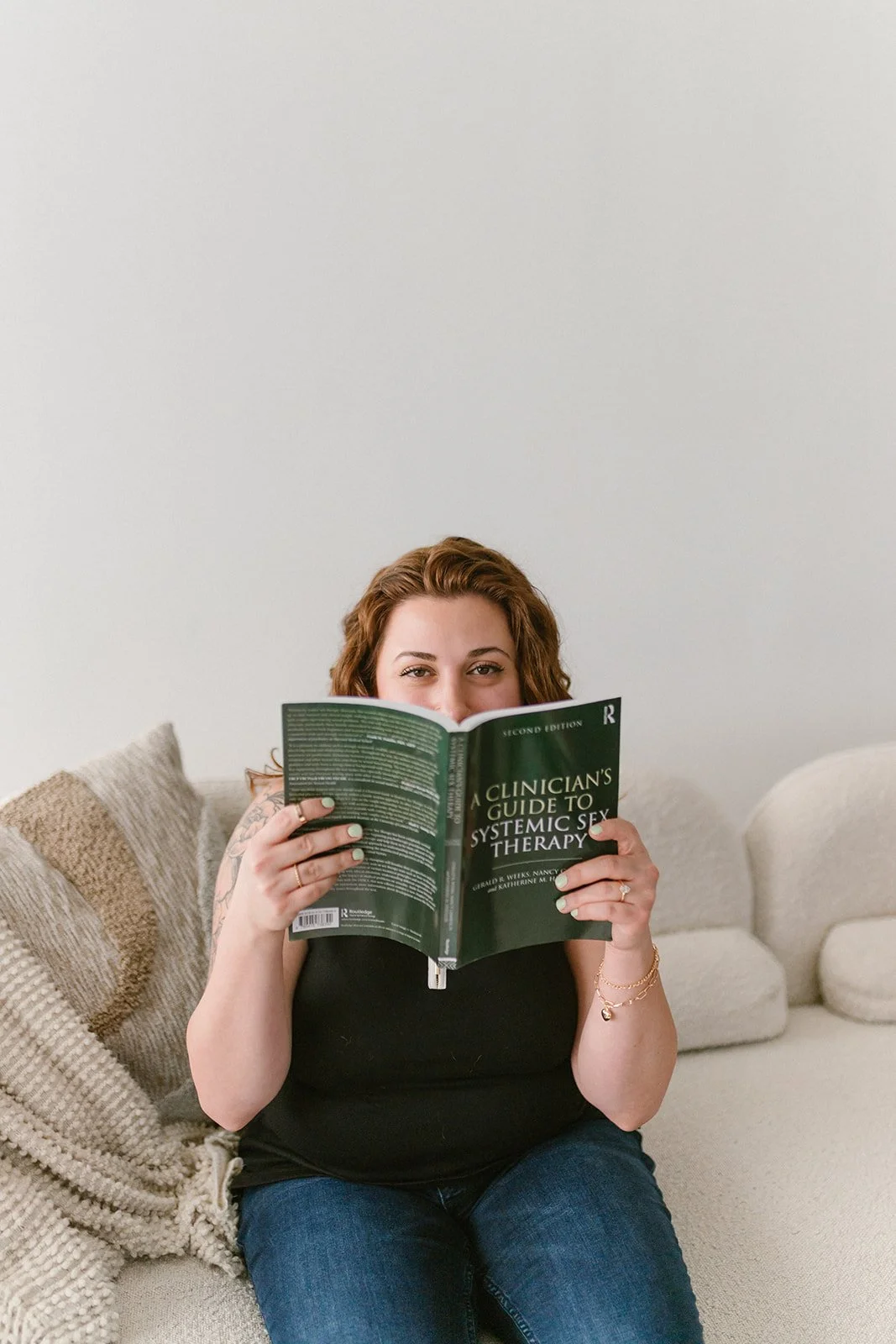 diana peeks over the top of a sex therapy book, ready to share her knowledge and experience with other therapists