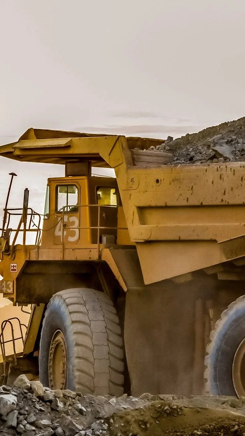 Una enorme excavadora amarilla moviendo tierra en un sitio de construcción.