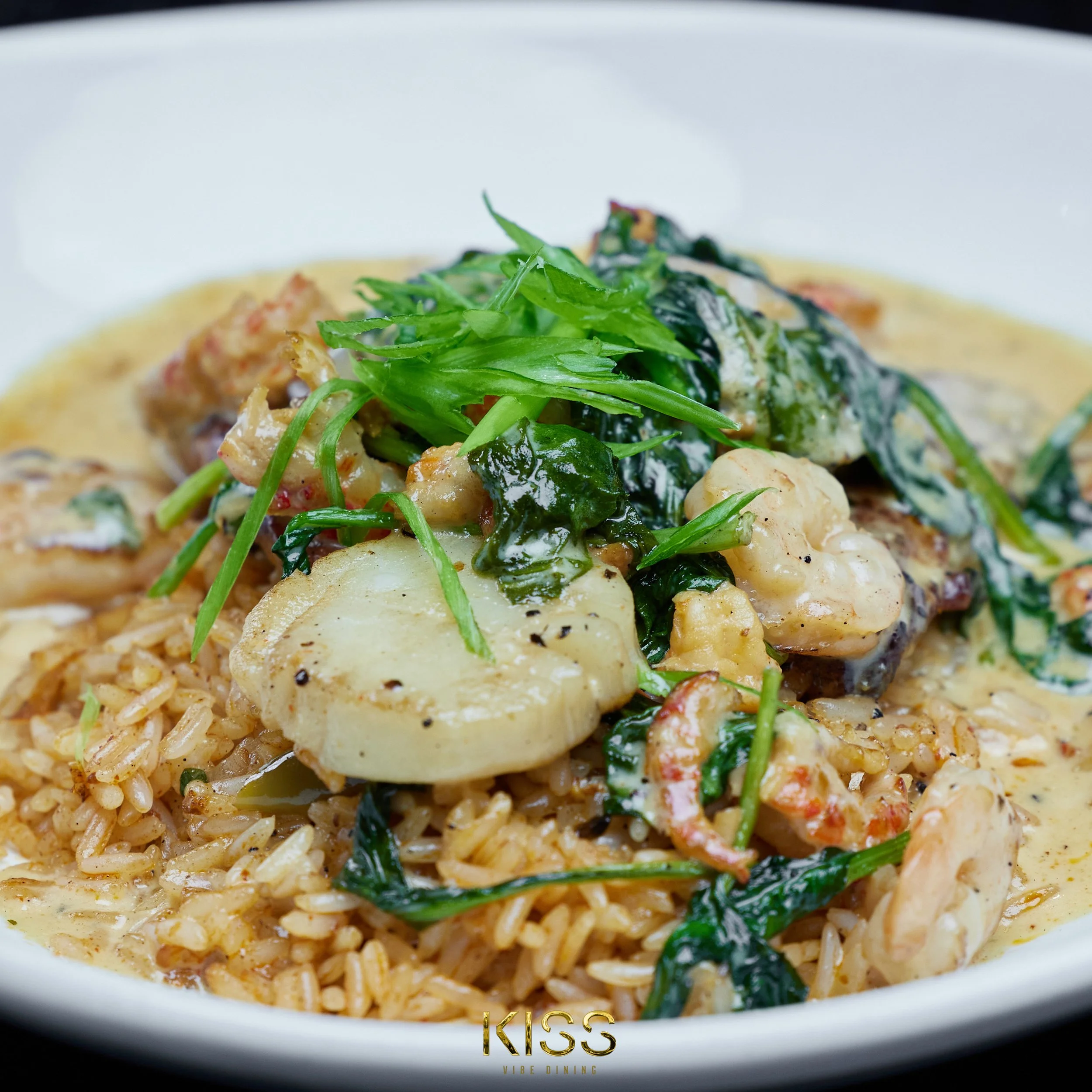 Close-up of a bowl of seafood risotto garnished with fresh greens.