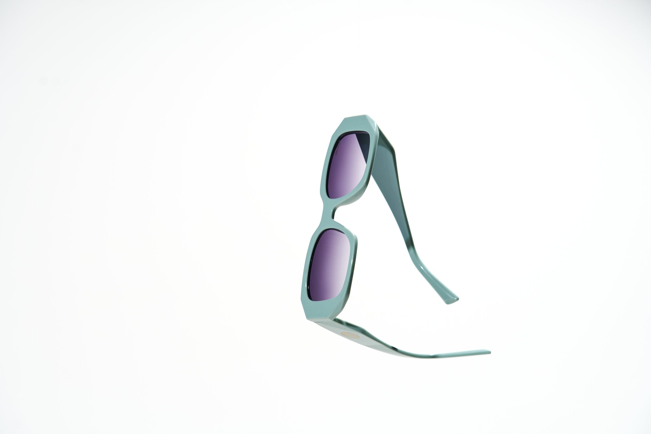 Stylish sunglasses with purple-tinted lenses and light blue frame on white background.