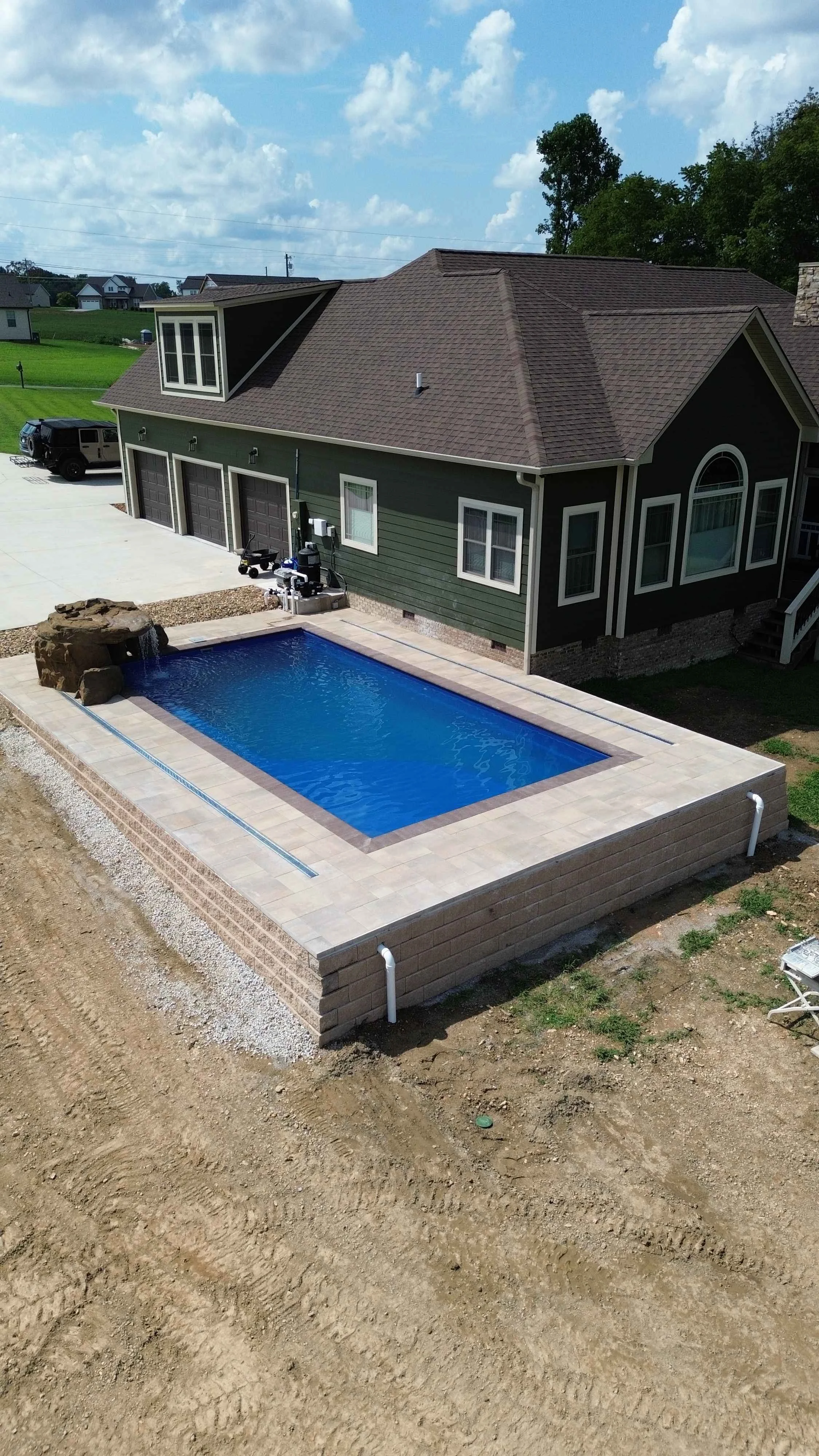 A backyard with a new swimming pool and a two-story house. 