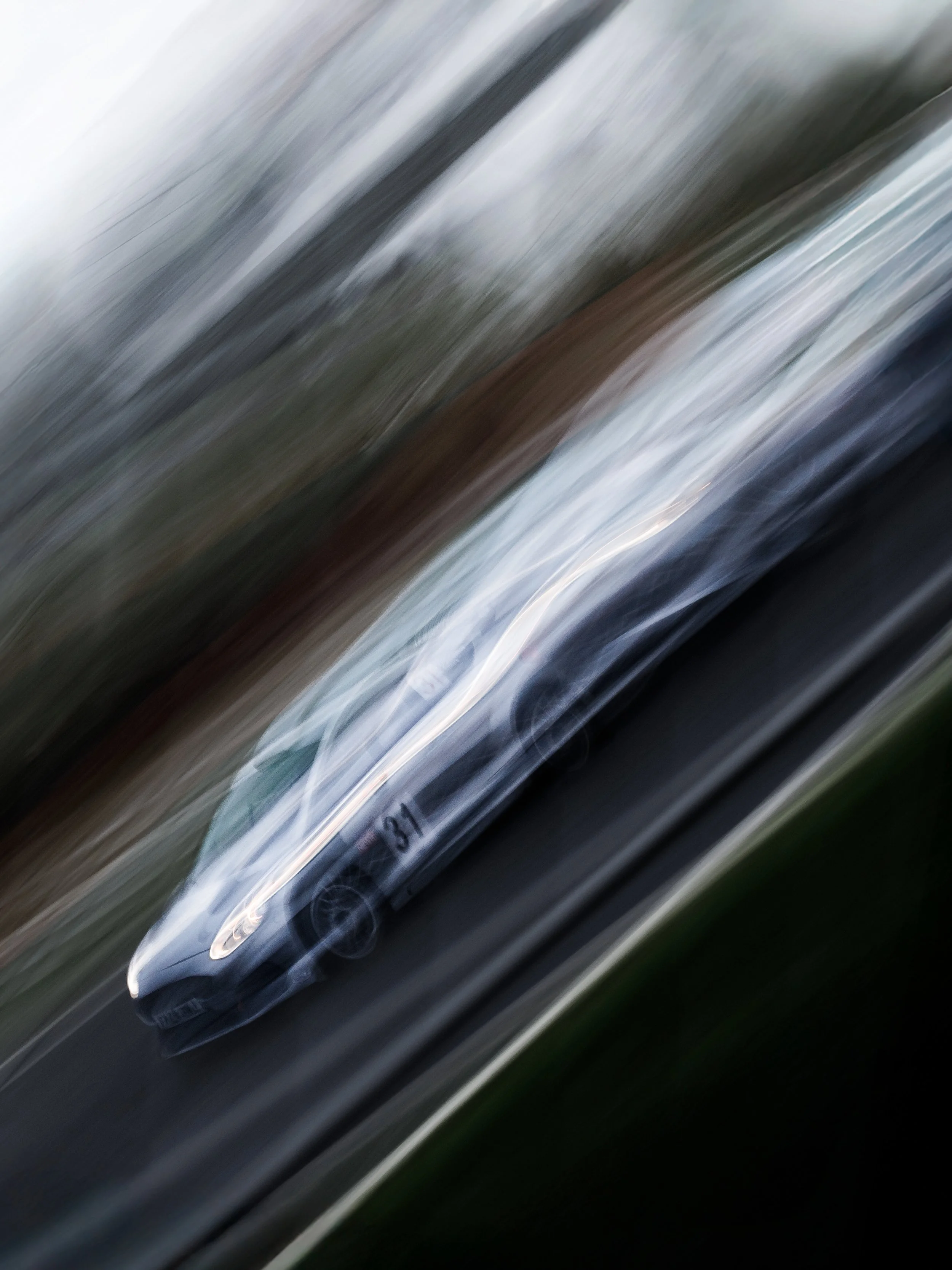 A car with racing decals and the number 31 speeding on a road, captured with motion blur.