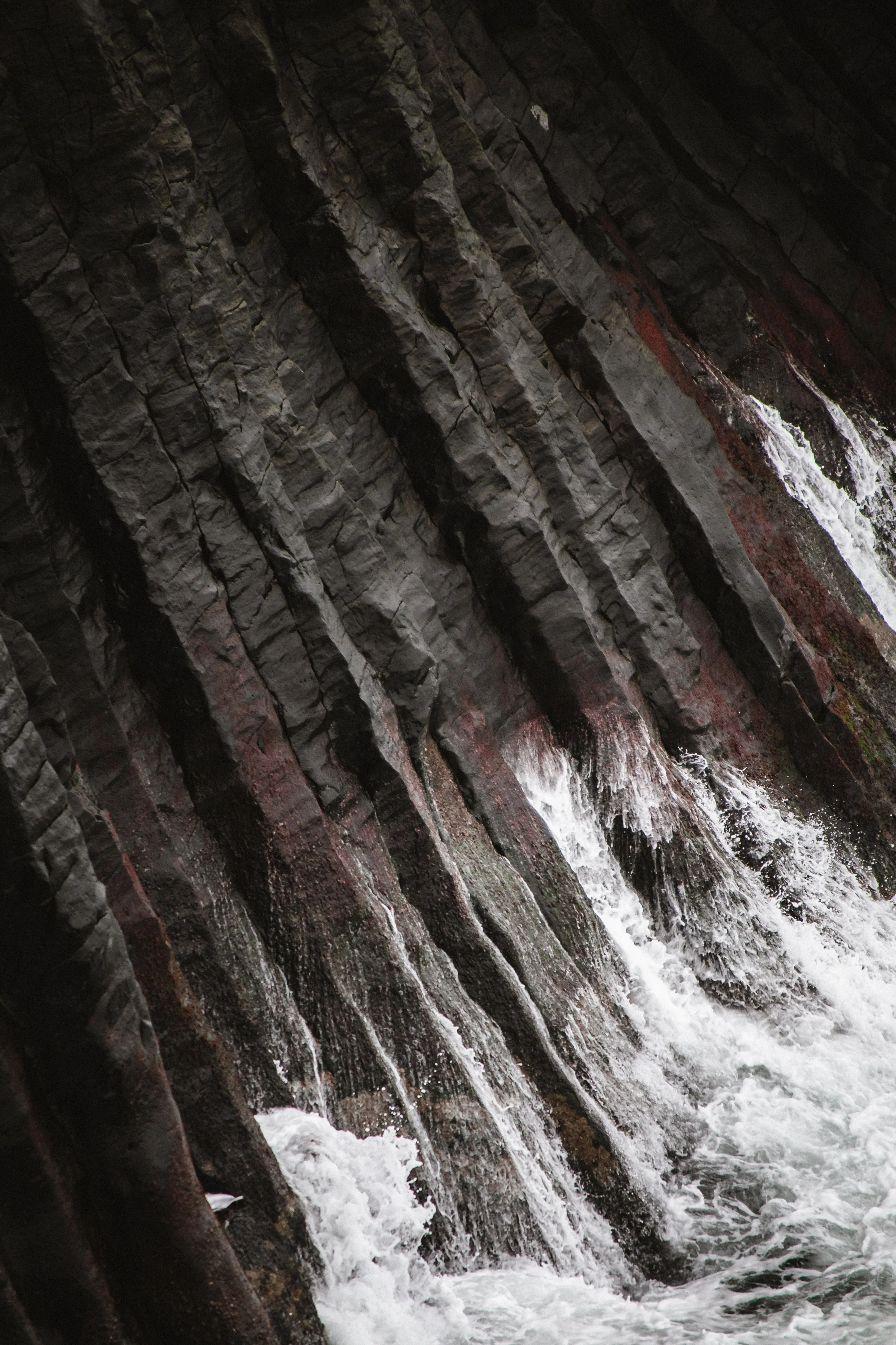 A view of a rocky waterfall with water cascading down over stone ledges.