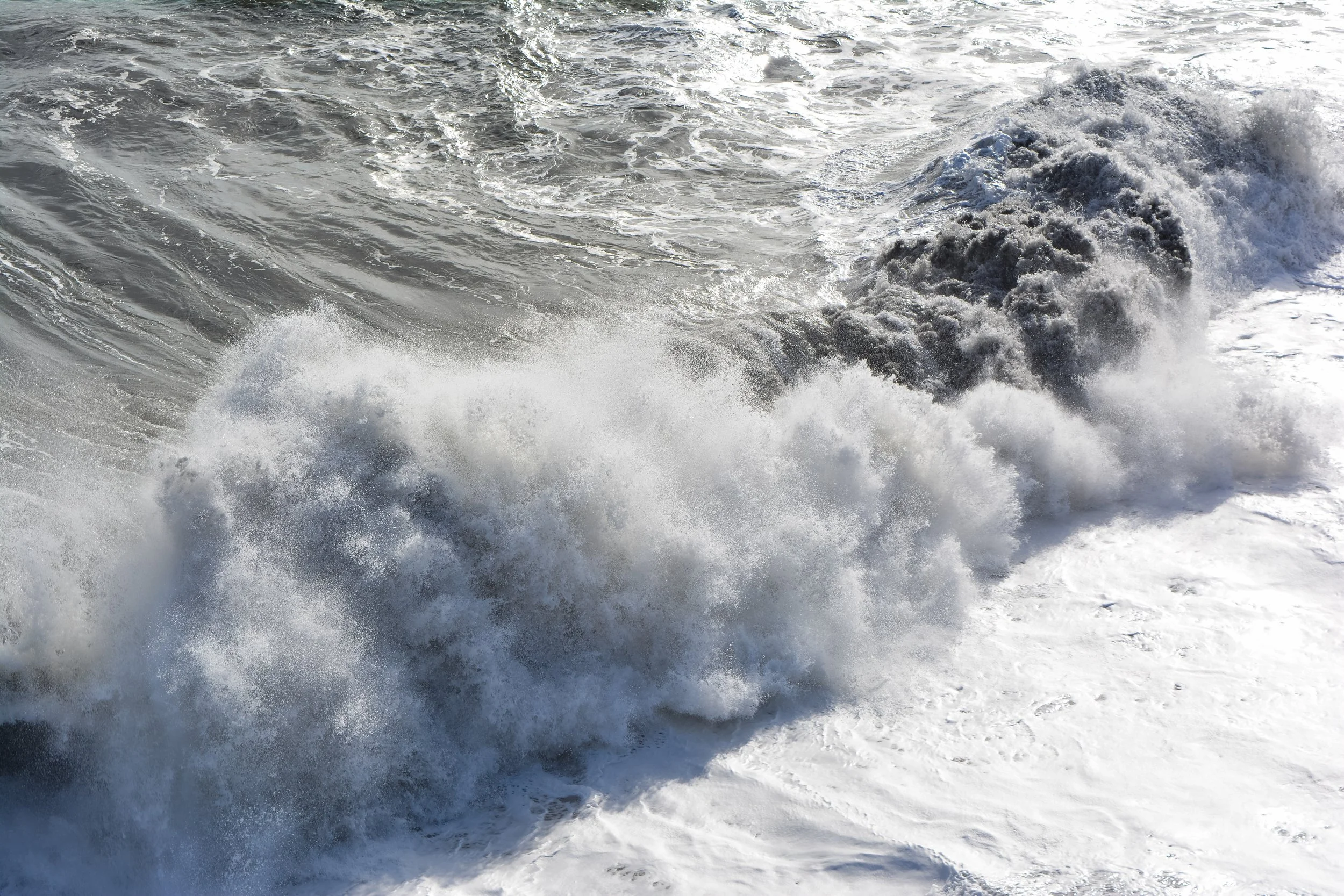 Waves crashing on the ocean shore with white foam and spray.