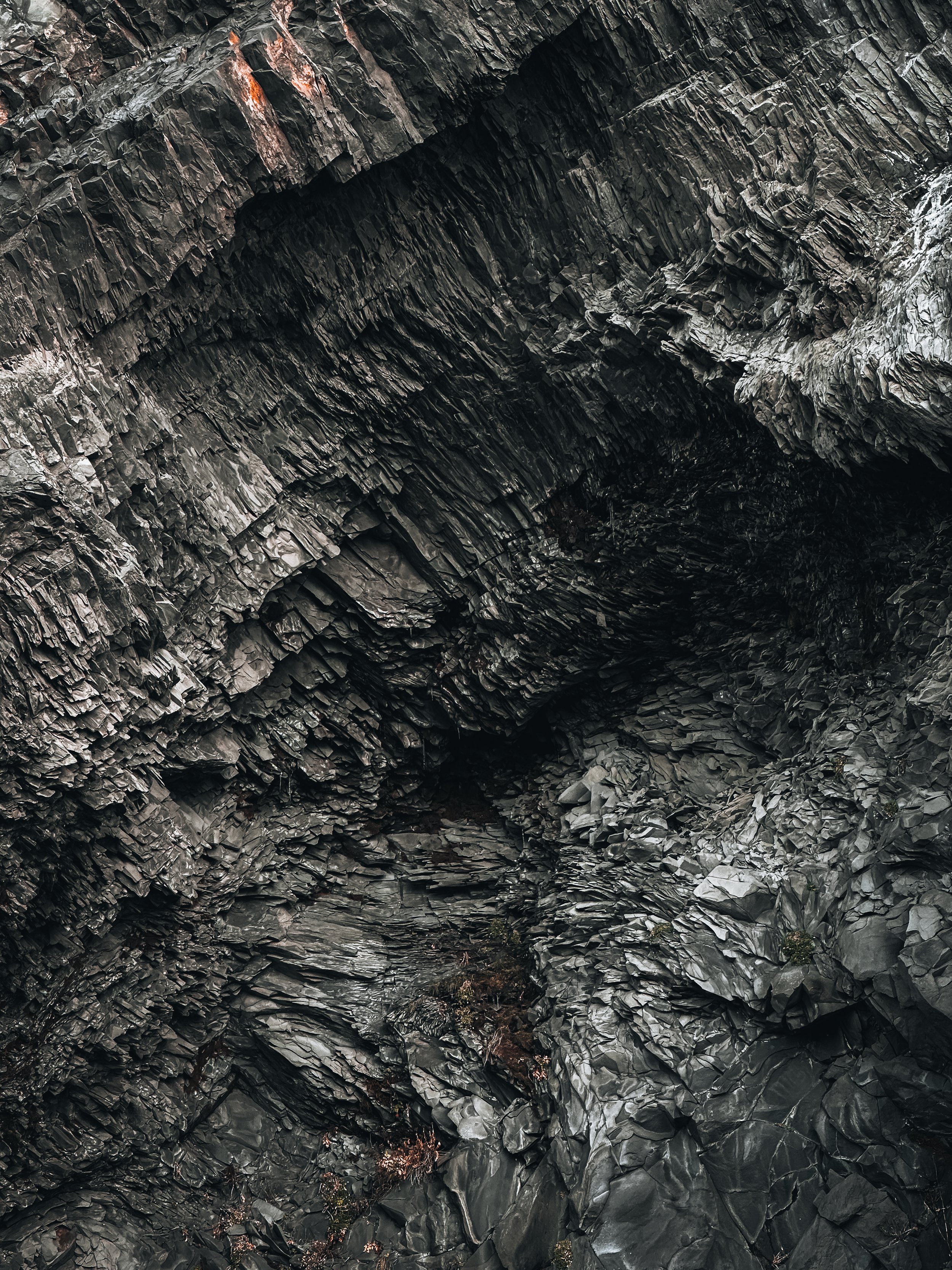 Close-up of dark, layered, and jagged rock formations in a cave or crevice.