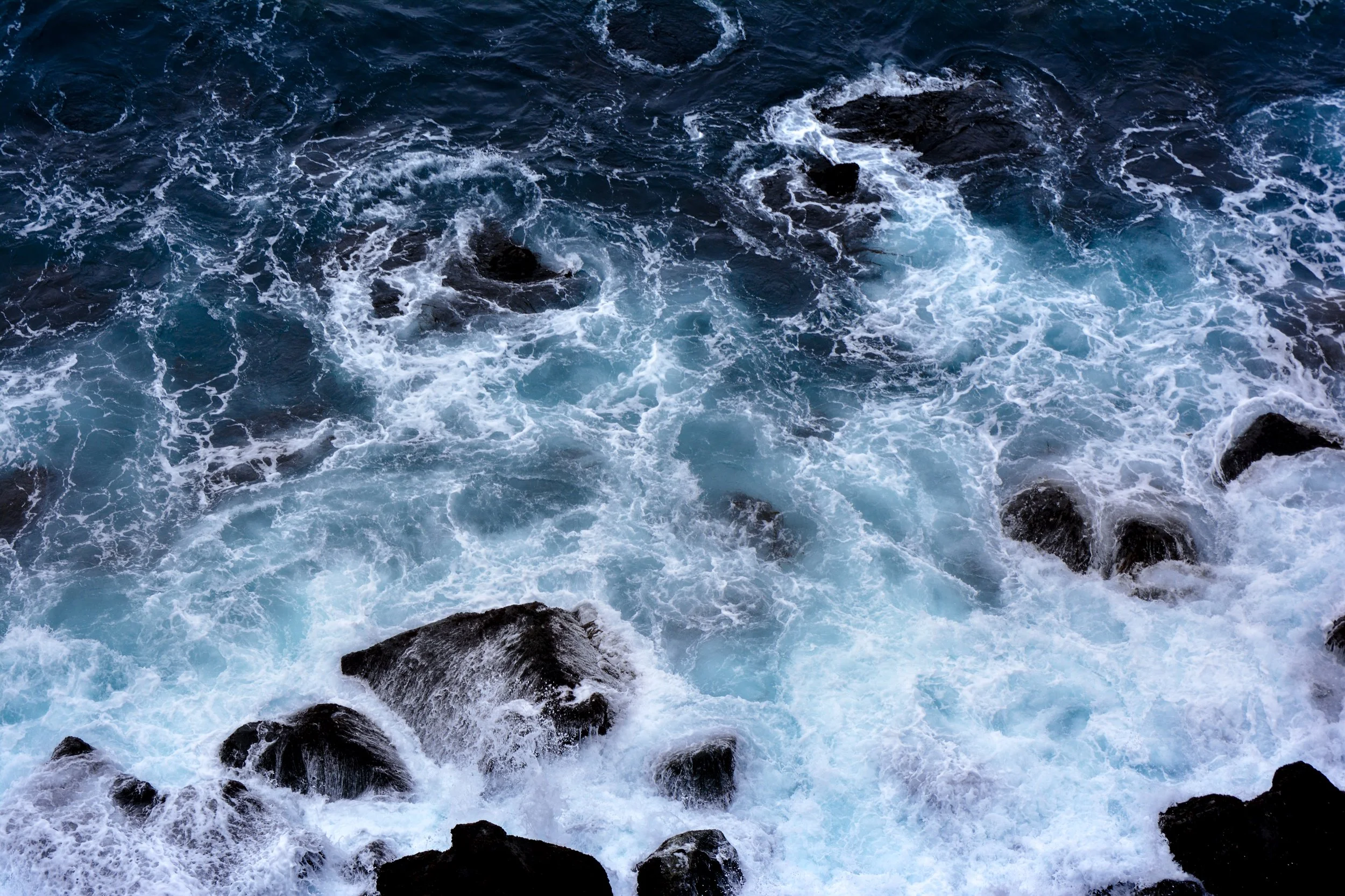 Ocean waves crashing against rocks with white foam.