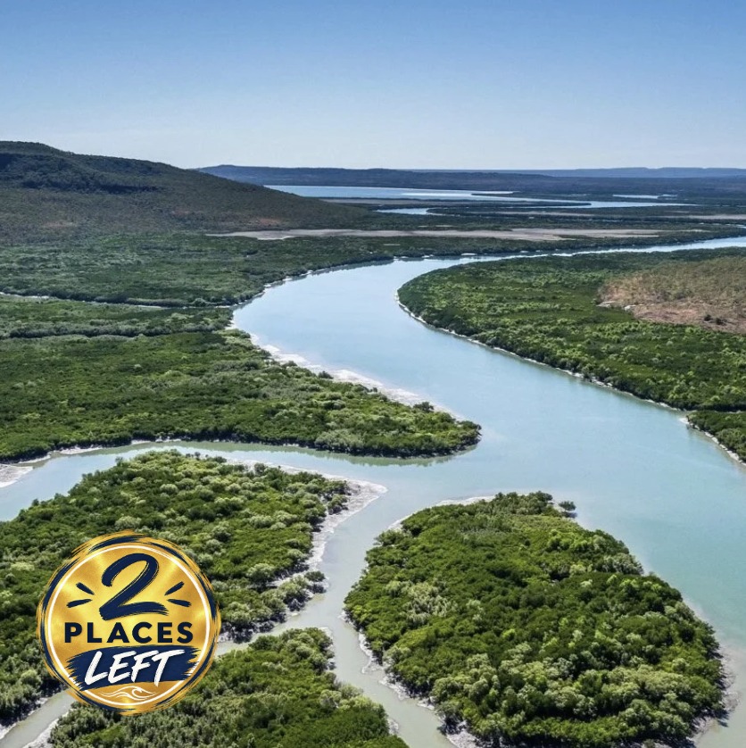 A winding river flowing through lush green landscape with hills in the background under a clear blue sky.