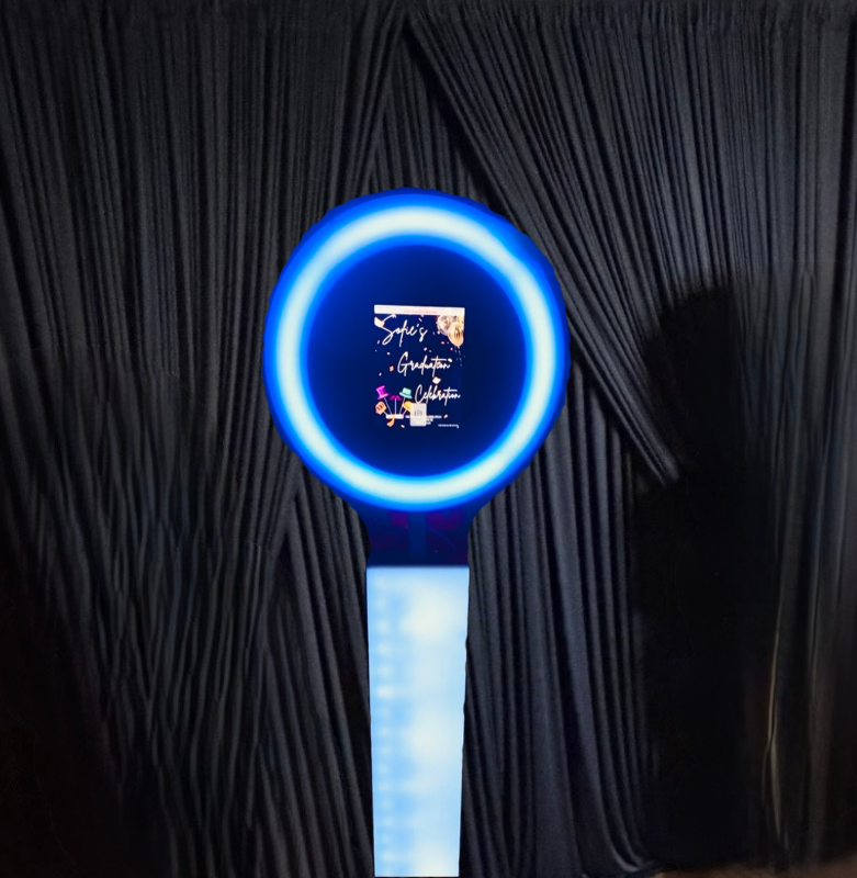 Blue illuminated device with a circular display, standing against a black curtain background, displaying text and graphics.