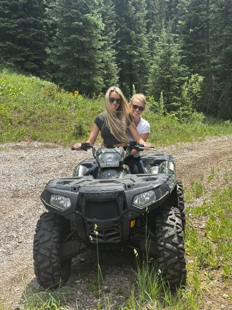 Summer and Coey riding the Polaris four-wheeler on a ranch road at 3 Peak Ranch