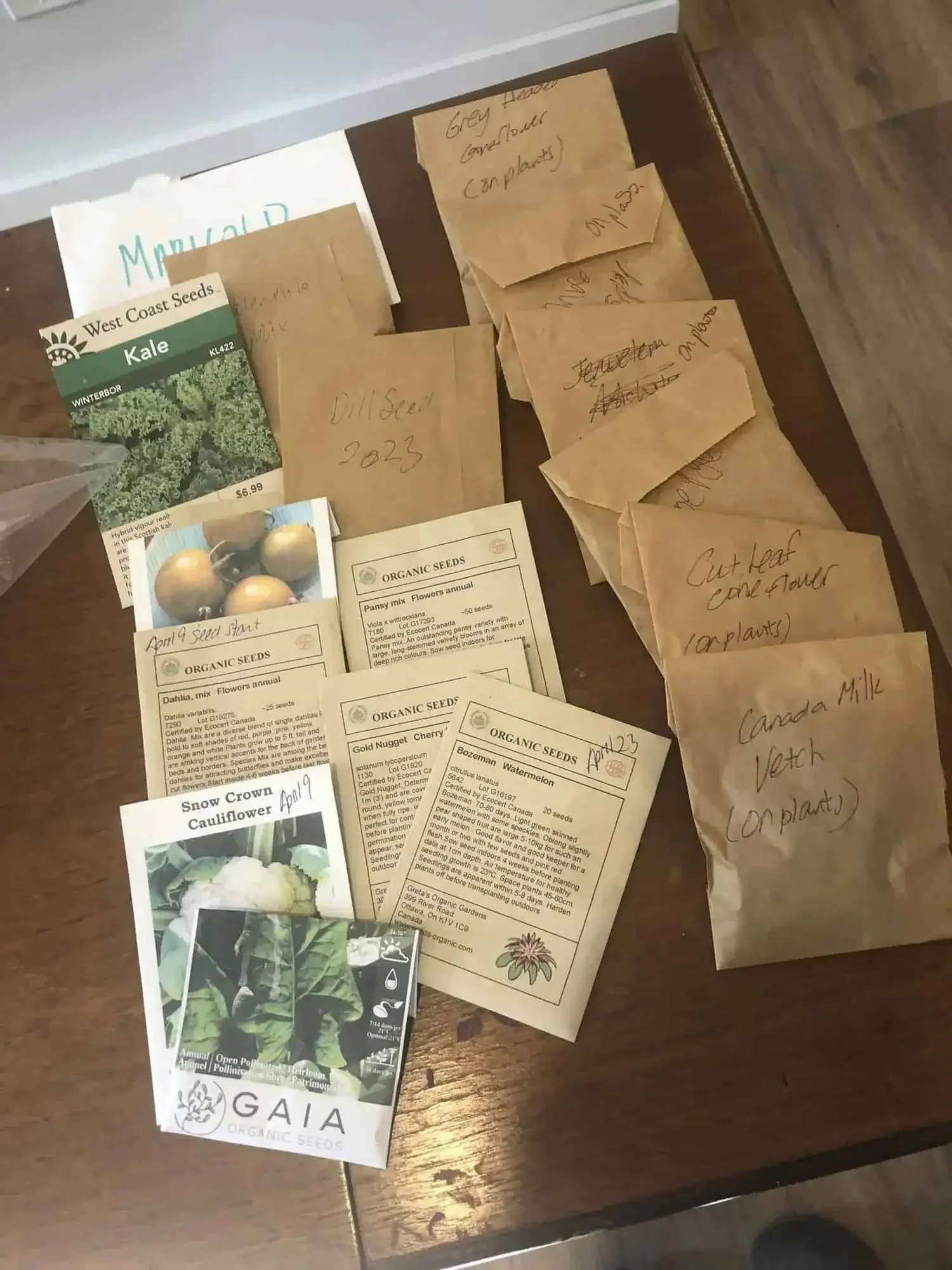 A table with a bunch of seeds in labelled packages set up for a seed sharing event at a forest garden in Quebec.