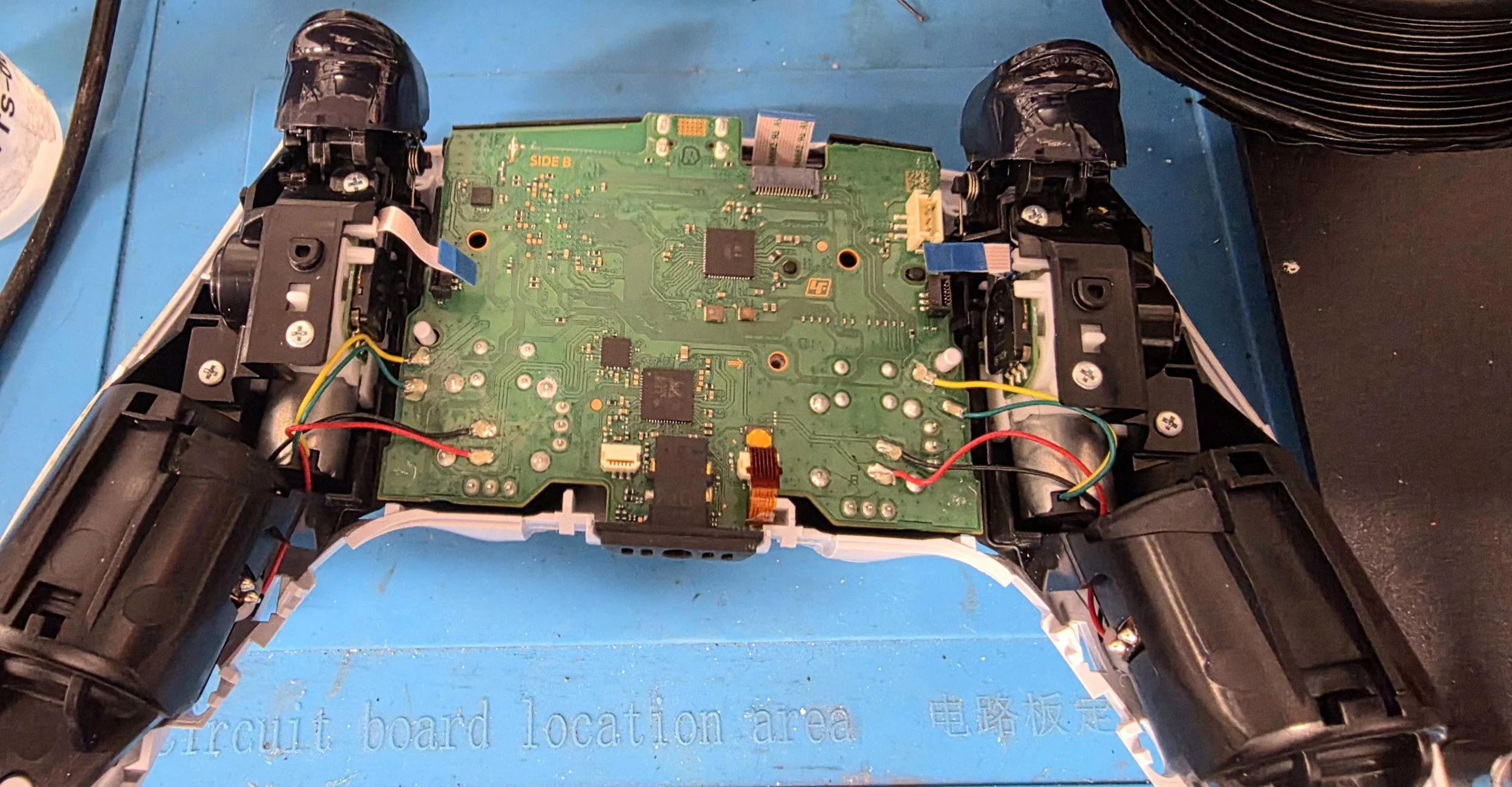 Inside view of a disassembled game controller showing the green circuit board and internal wiring.