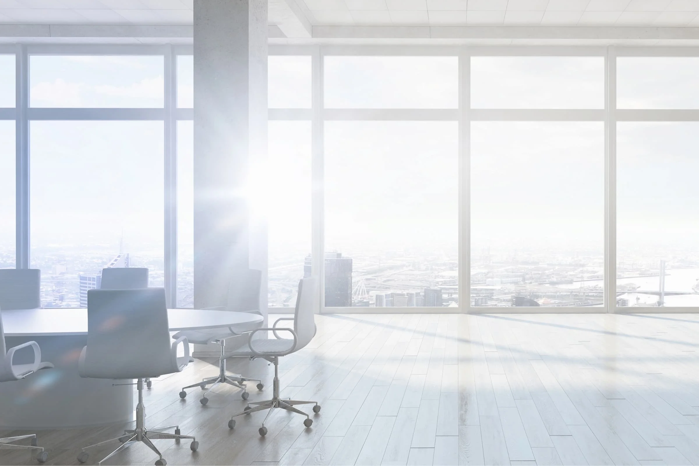 Modern office conference room with large windows showing city skyline, office chairs around a conference table, and a light-colored wooden floor.