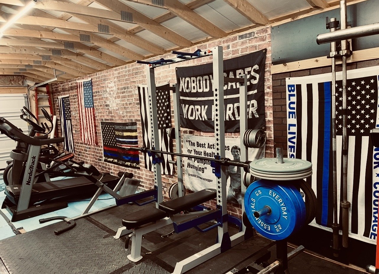 Home gym with treadmill, weightlifting equipment, and American flags on the wall.