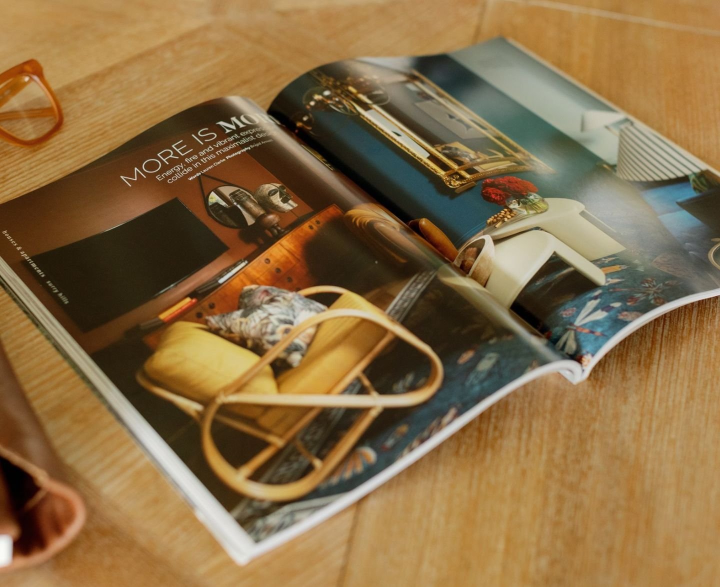 Open magazine displaying interior decor with colorful furniture and artwork on a wooden surface.