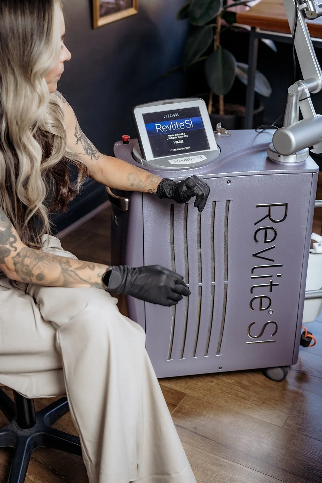 Technician operating RevLite SI laser machine used for tattoo removal inside studio setting