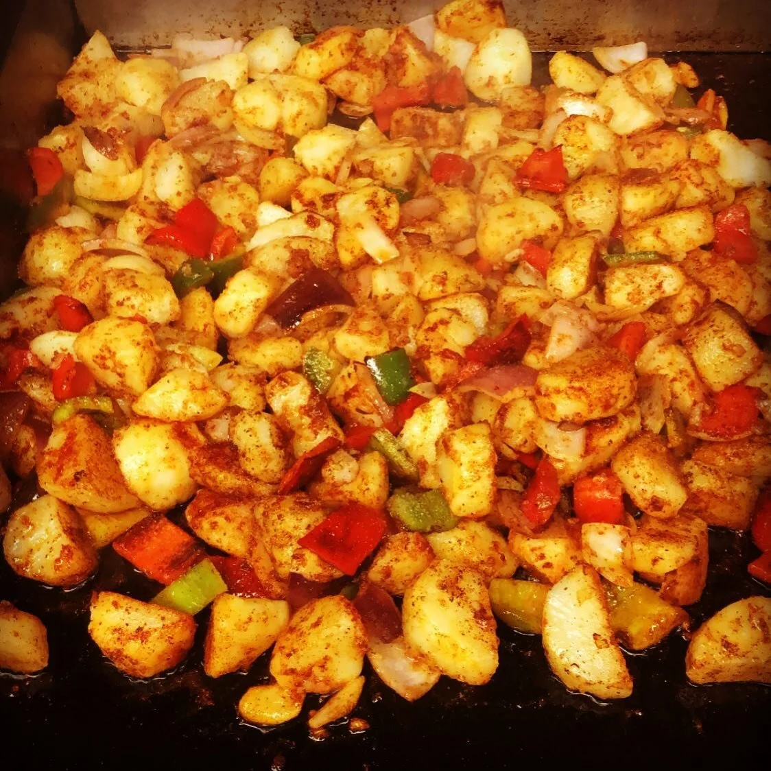Cooked diced chicken with bell peppers, onions, and spices in a skillet.