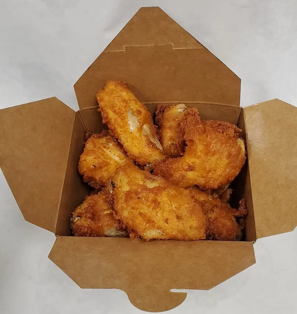 Fried chicken pieces in a brown cardboard takeout box.
