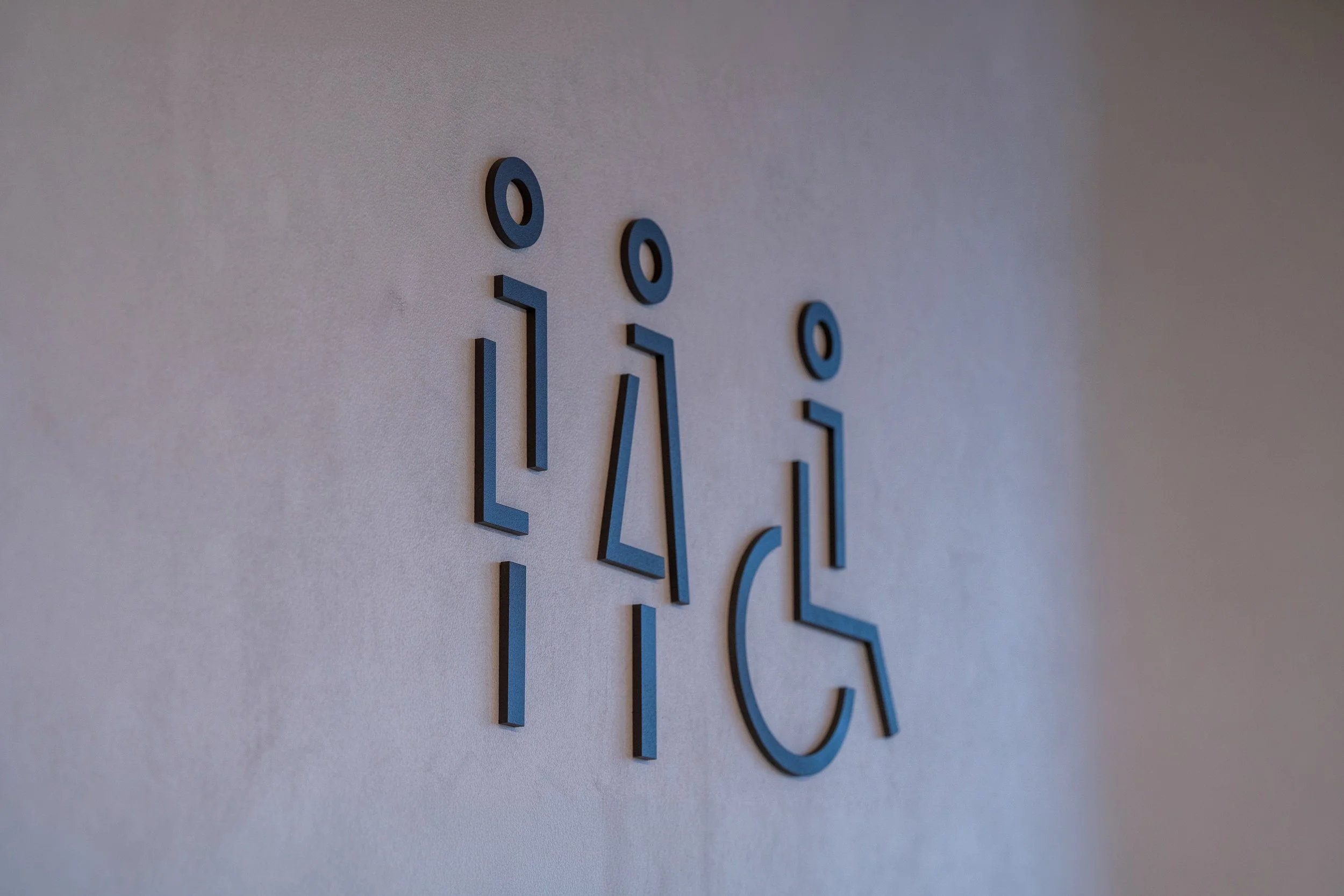Close-up of a modern wall clock with blue numbers on a light-colored wall.
