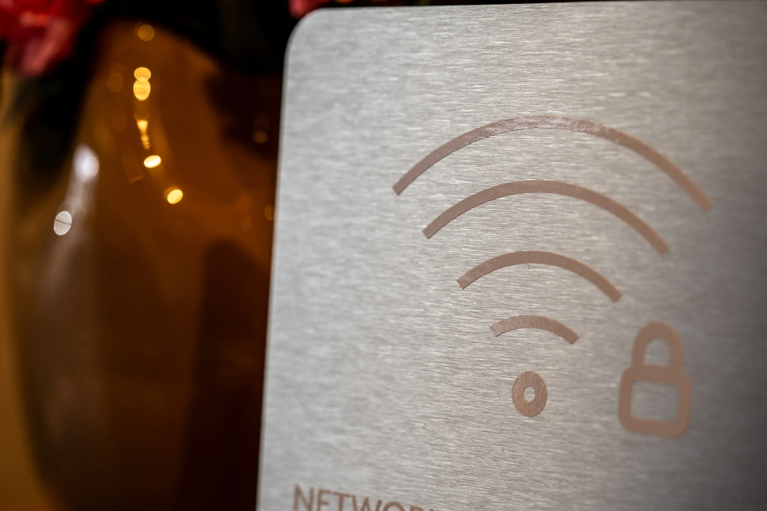 Close-up of a metallic surface with a faint rainbow-colored logo and an amber-colored glass bottle with a red cap reflected on the surface.