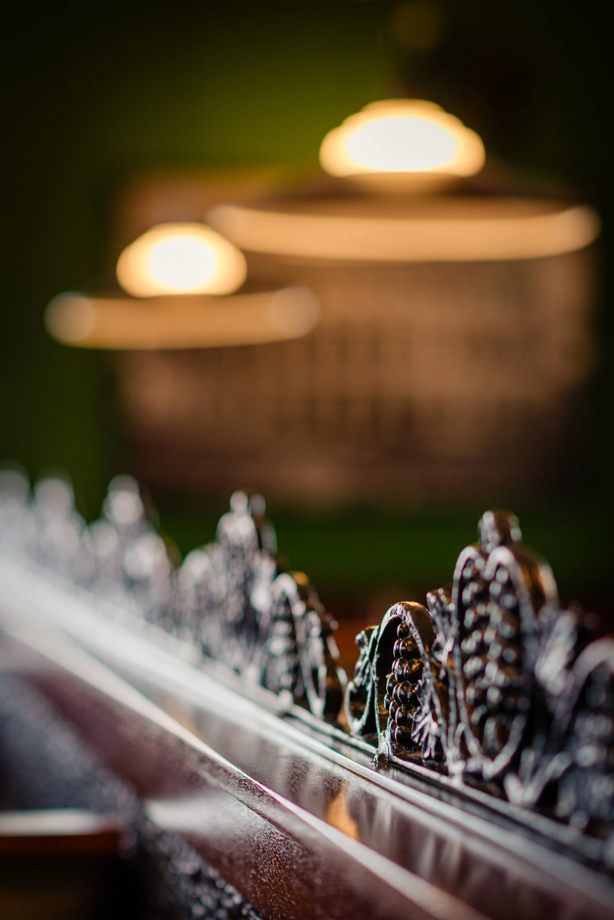 Close-up of ornate metalwork on a decorative object with blurred warm lighting in the background.