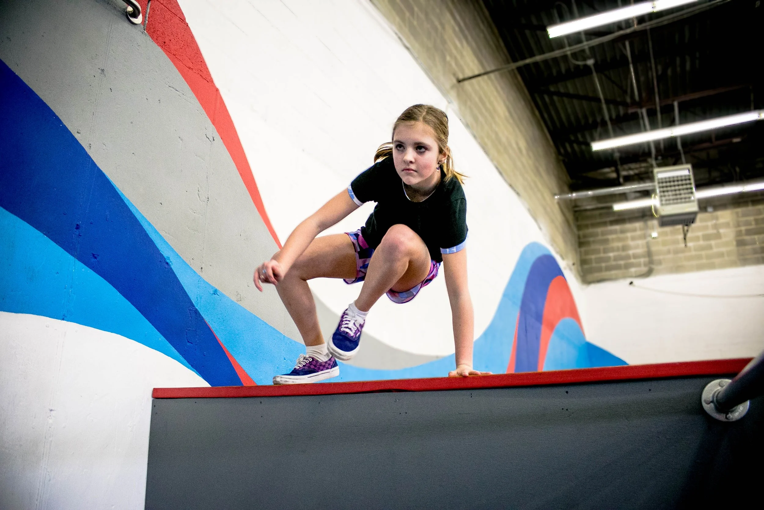 A young parkour student moving confidently over an indoor obstacle
