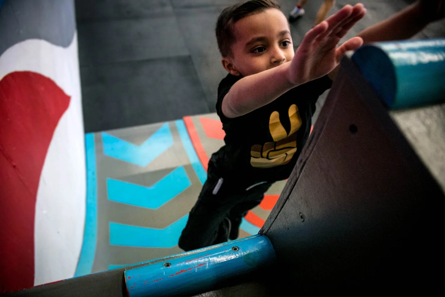A young parkour student climbing through a colorful indoor obstacle