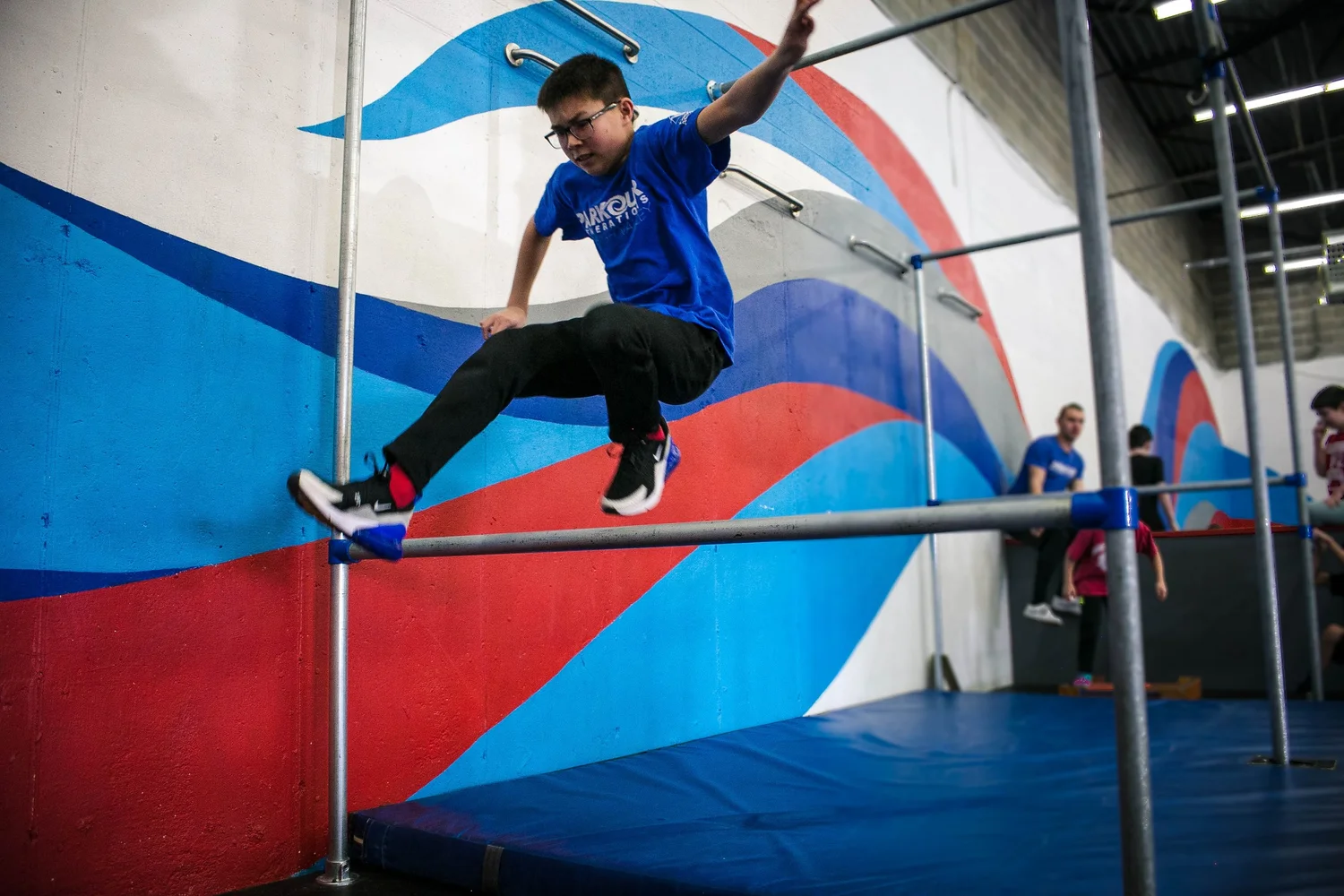 A youth parkour student practicing a controlled rail movement indoors