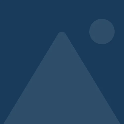 Silhouette of a mountain with a round moon or sun in the night sky.