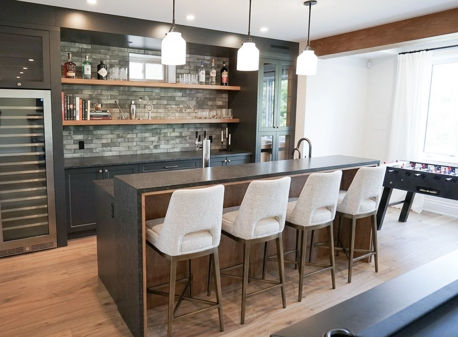 basement bar with iron ore custom cabinetry and granite waterfall countertop