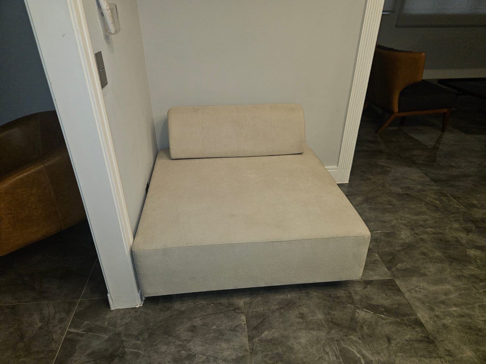 Sofá de canto bege na sala, com piso de cerâmica escura.