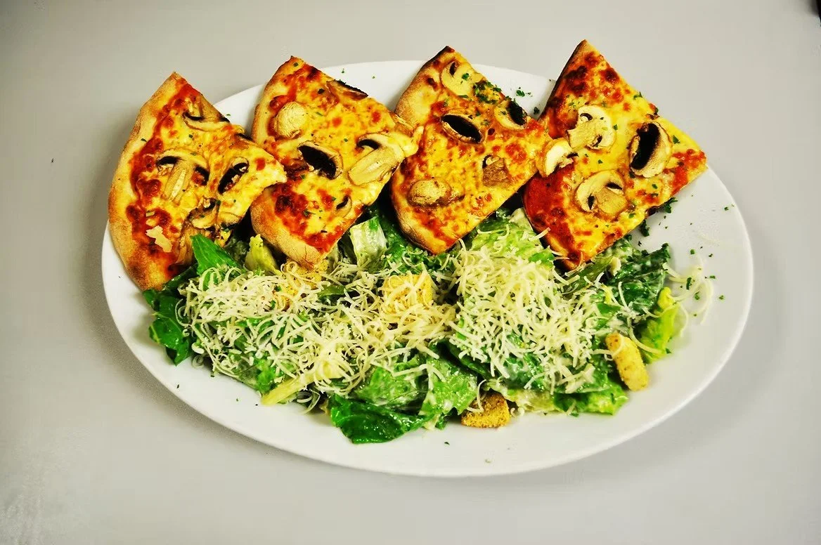 Plate with four slices of mushroom and cheese pizza and a side salad with shredded cheese.
