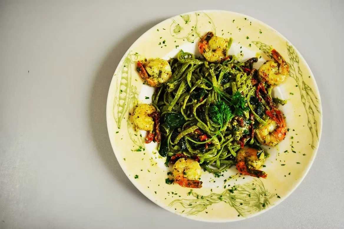 Plate of shrimp and spinach pasta garnished with parsley