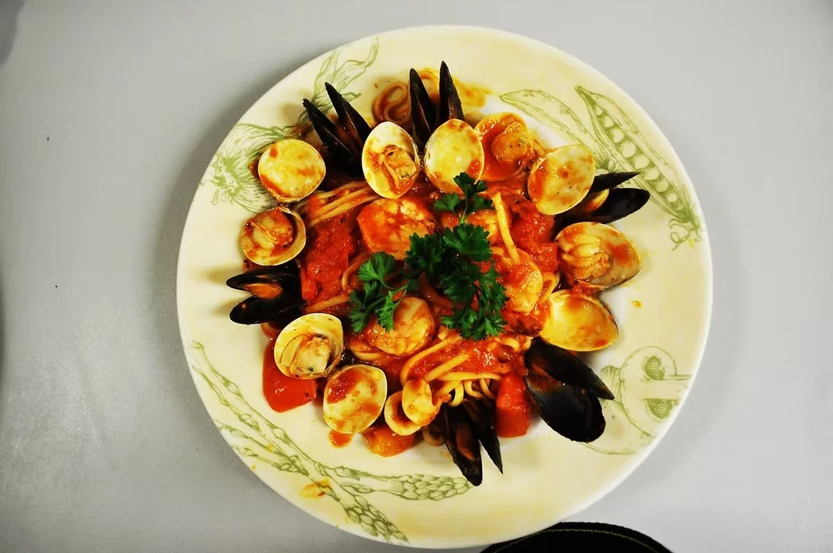 Plate of seafood pasta with shrimp, clams, mussels, and garnished with parsley.
