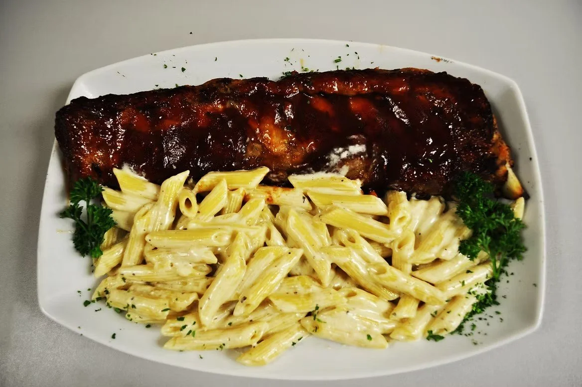 Baked chicken breast with barbecue sauce and a side of creamy pasta with parsley garnishes