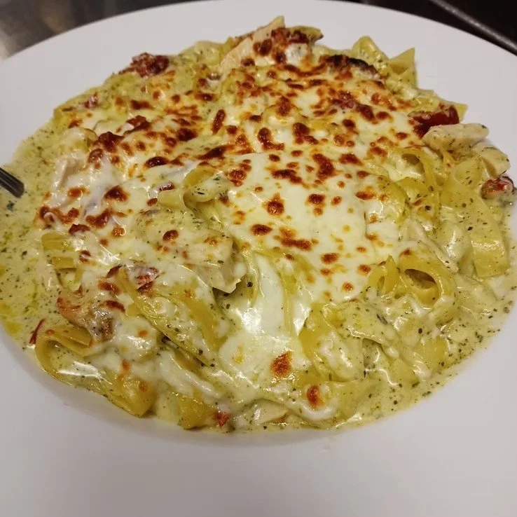 Baked pasta with melted cheese and creamy sauce on a white plate.