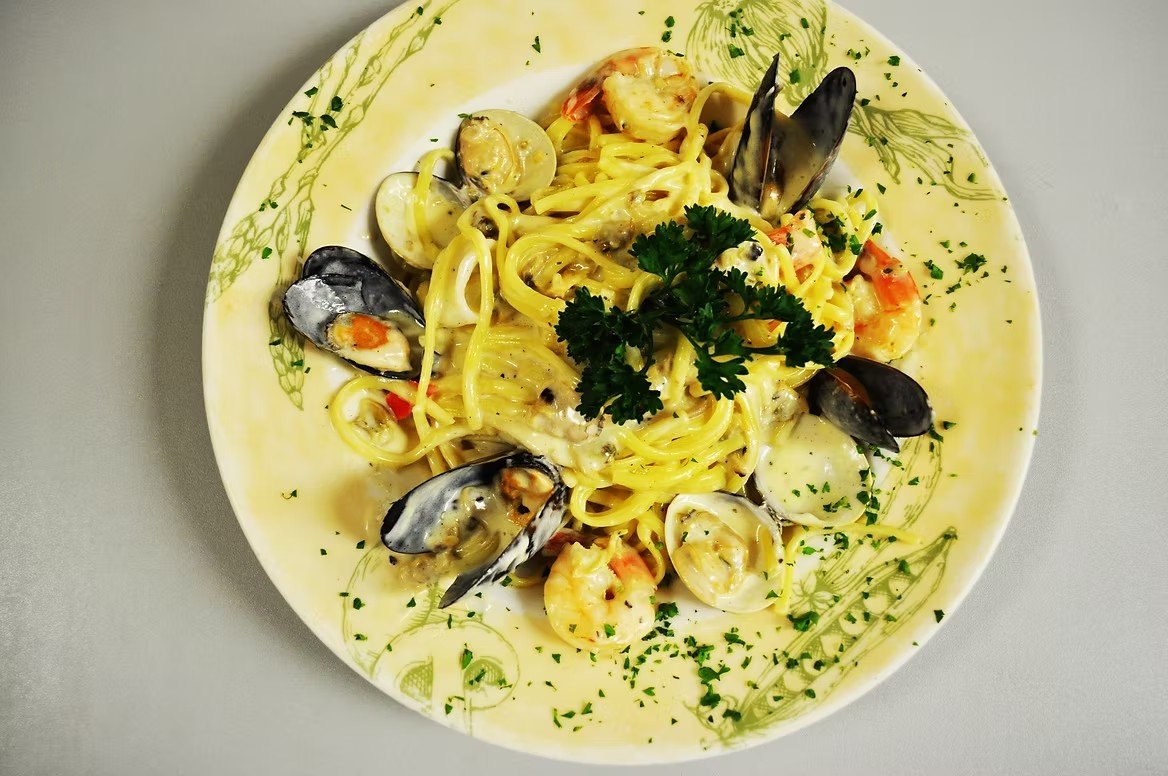Plate of seafood pasta with shrimp, mussels, and clams garnished with parsley.