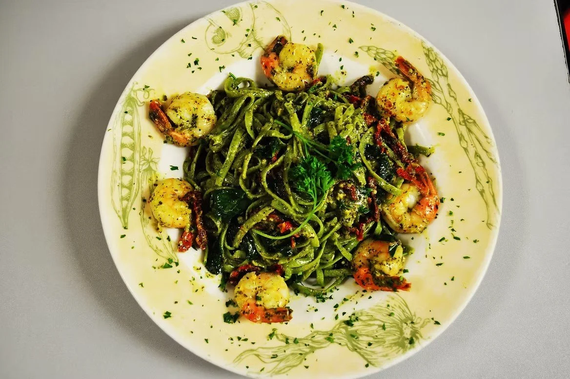 Plate of shrimp and spinach pasta garnished with parsley.