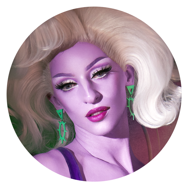 Headshot of Miz Cracker in purple makeup and a large blonde wig