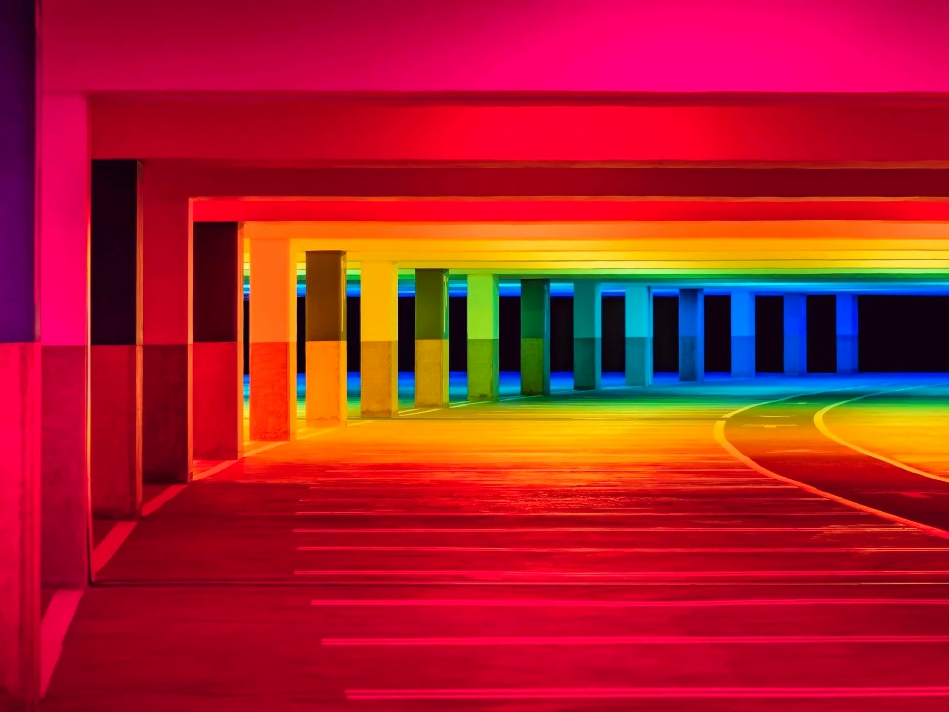 Colorful rainbow-lit tunnel under a bridge with rainbow columns and a curved road.