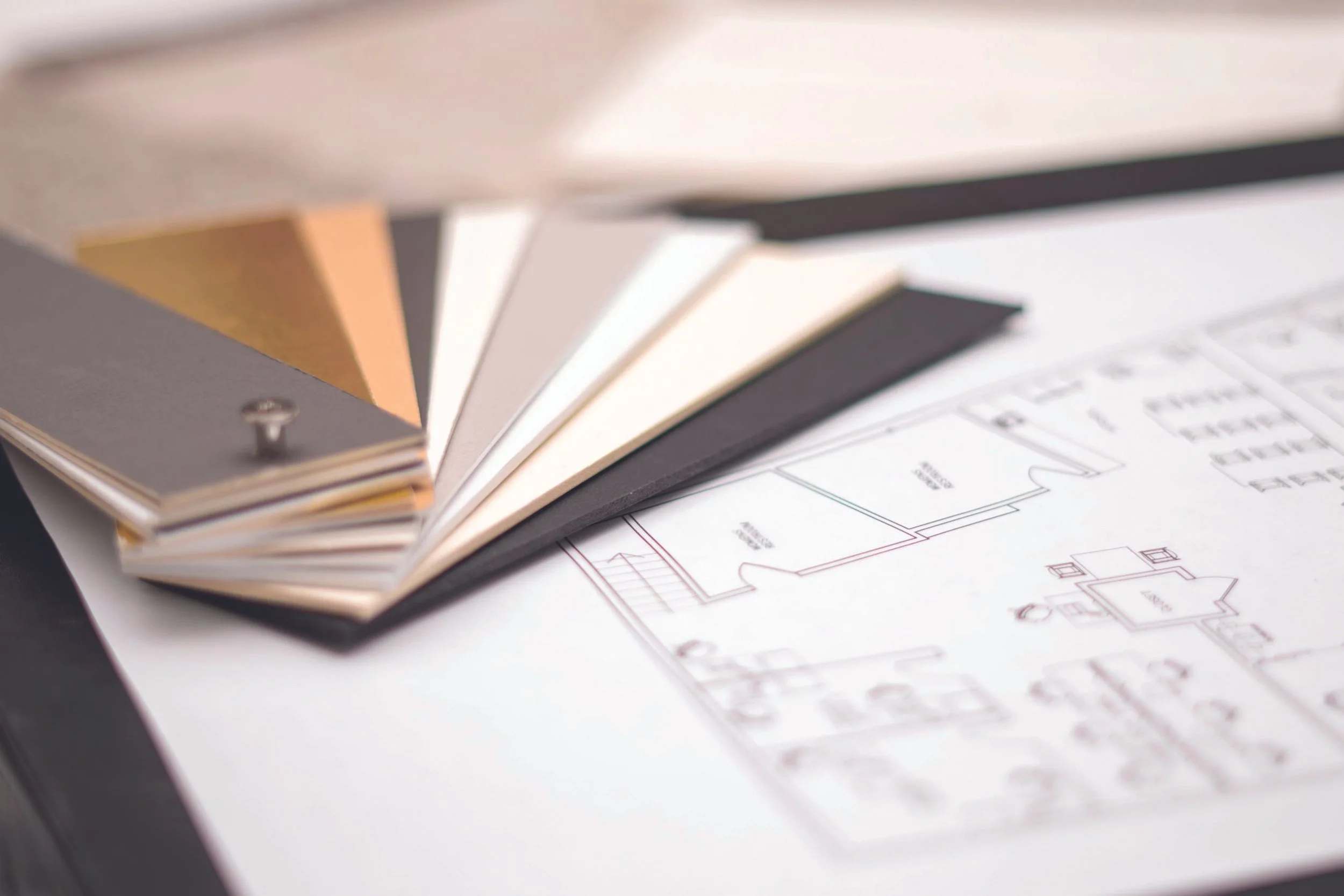 Samples of paint color swatches fanned out over a detailed home floor plan drawing.