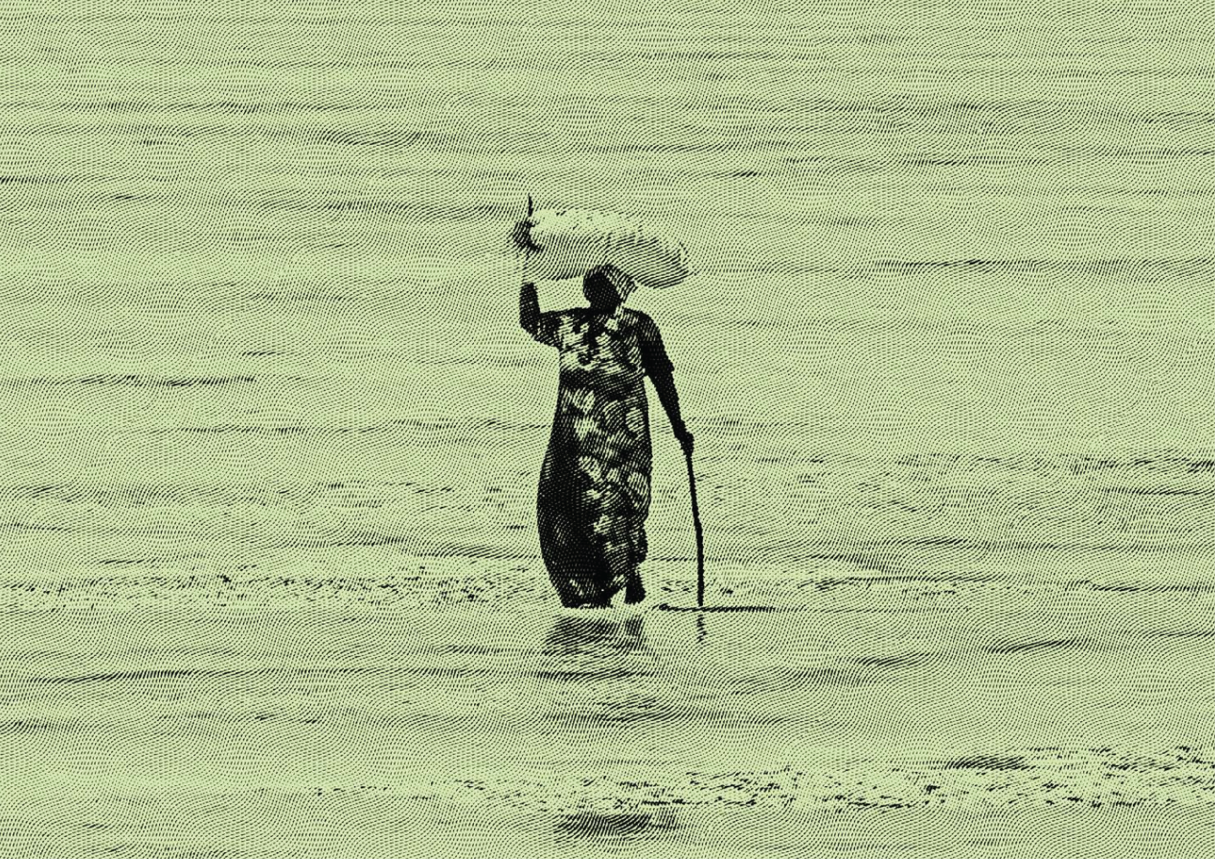 Silhouette of a woman walking in water with an umbrella during the day.