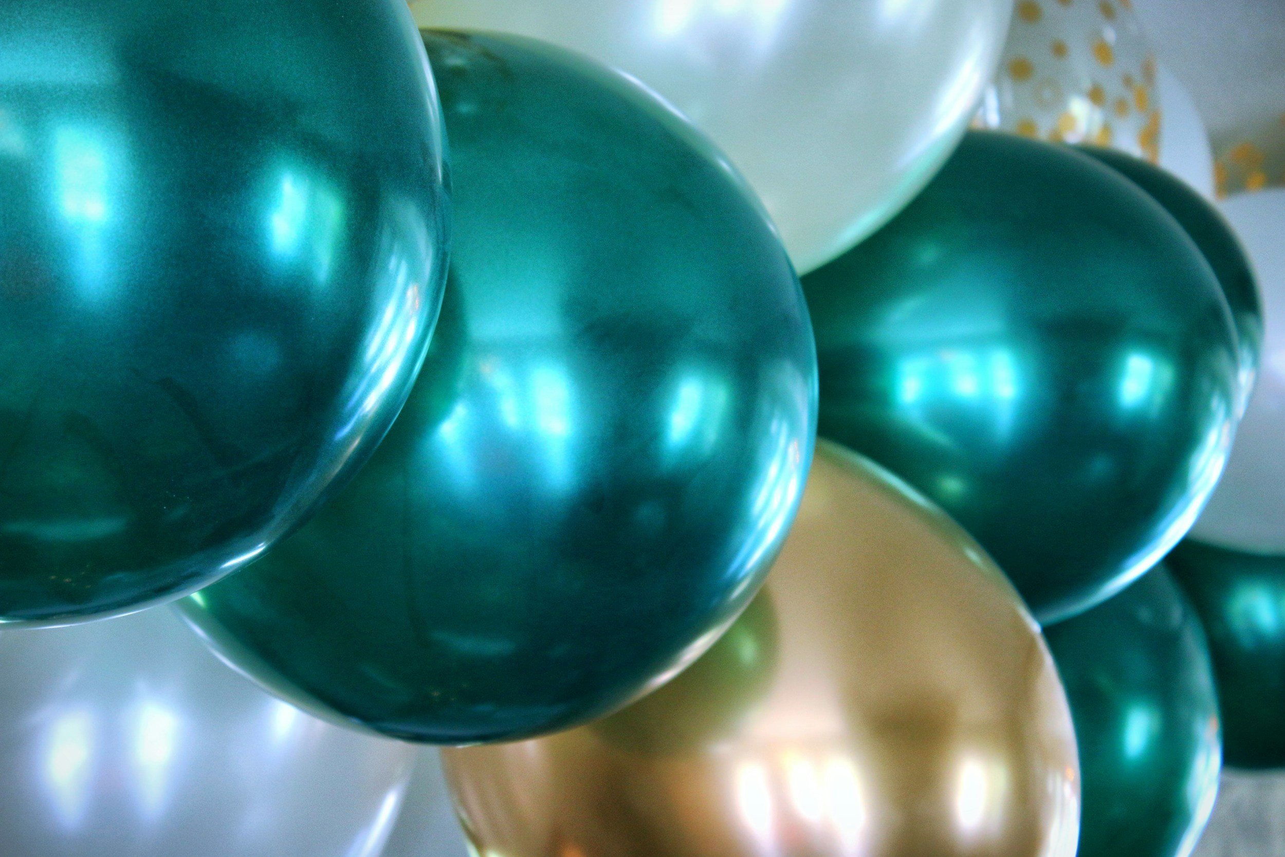 Close-up of teal-colored balloons with shiny, reflective surfaces.