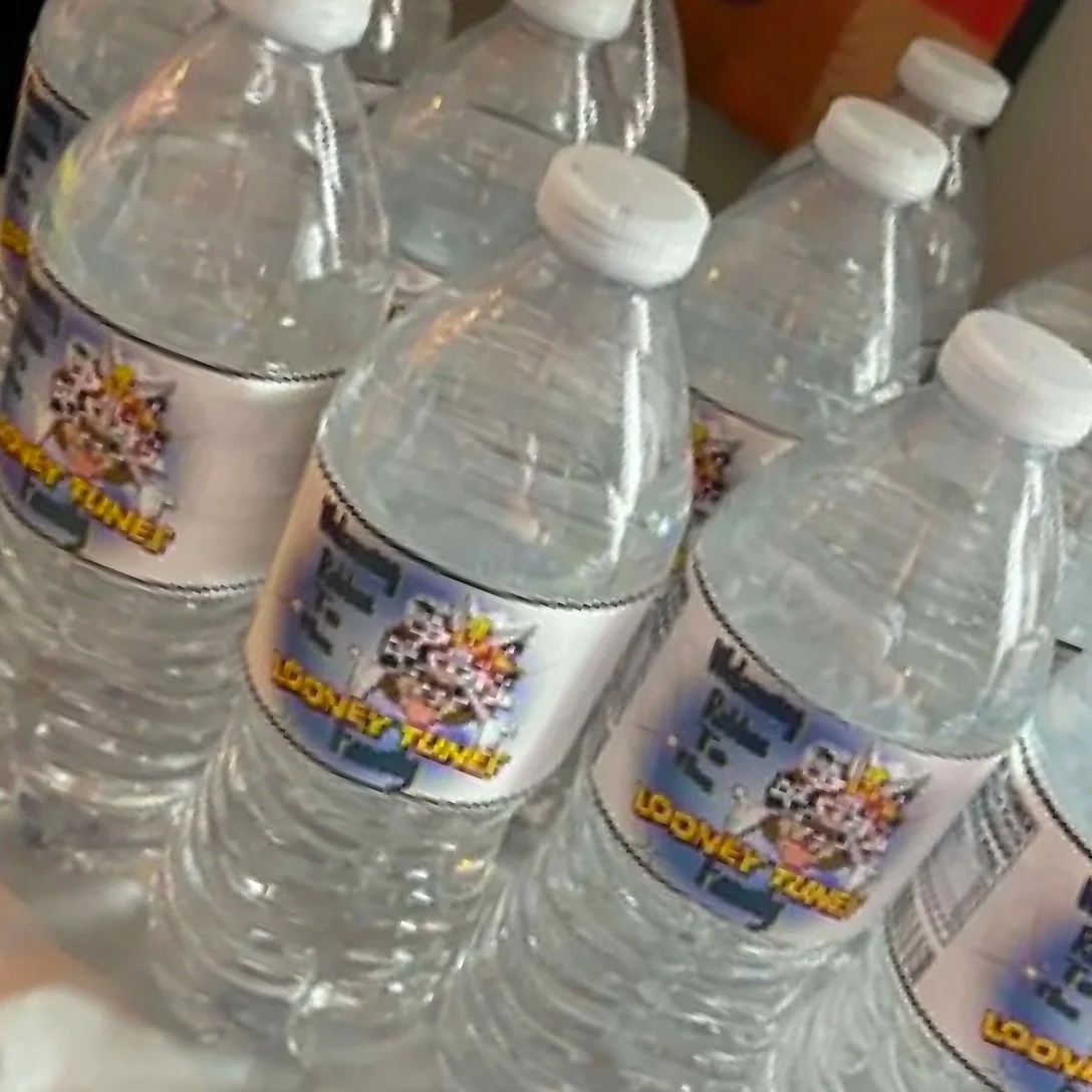 Several bottles of bottled water with colorful labels and white caps arranged on a surface.
