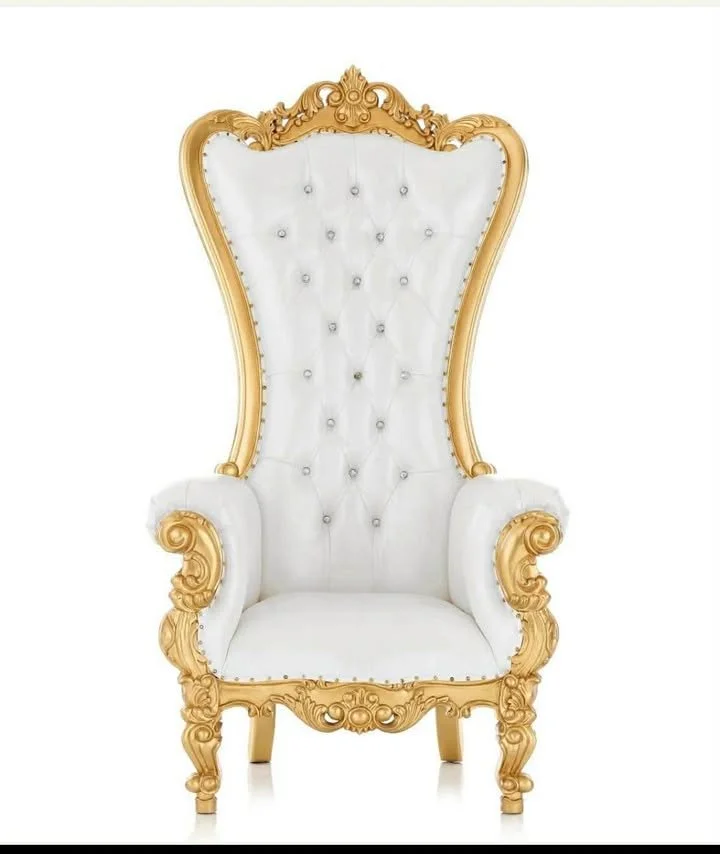 A luxurious white and gold throne chair with intricate carvings and button-tufted upholstery.
