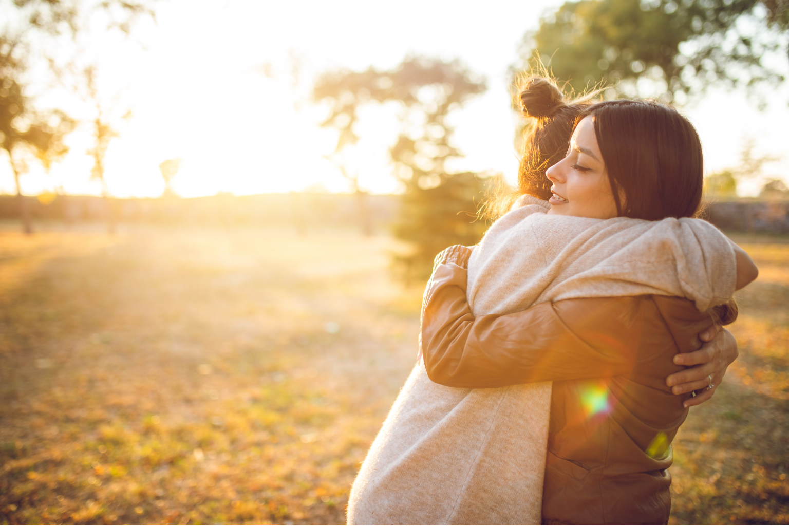Two women hugging each other in a tight embrace during sunset.